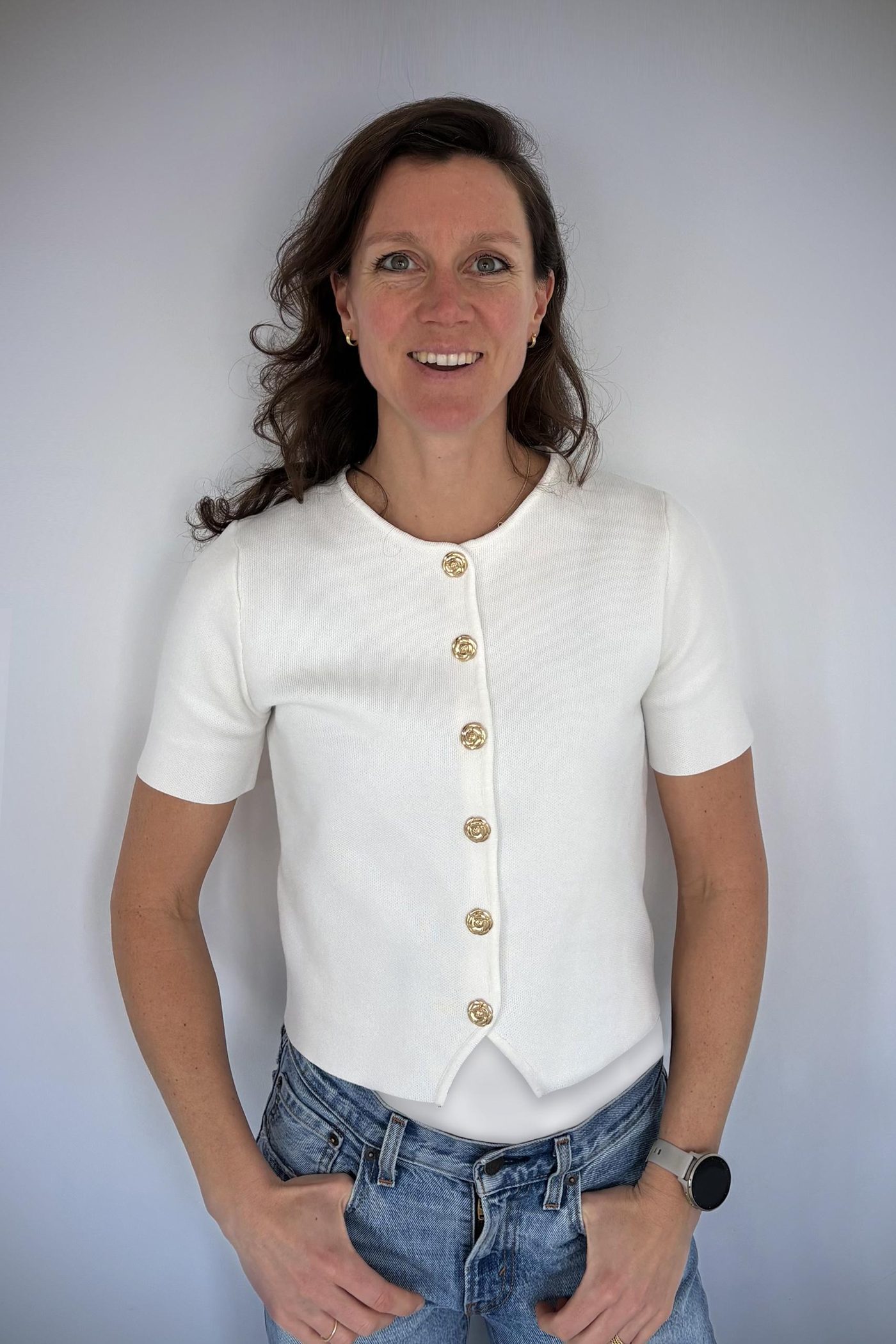 Portret van Rosanne Vermeulen, lachend, in een witte blouse tegen een lichte achtergrond